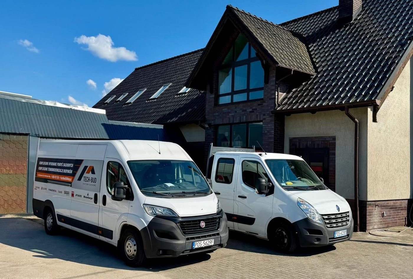 Siedziba firmy TECH-BUD w Ostrowie Wielkopolskim z dwoma busami firmowymi przed budynkiem z ciemną dachówką